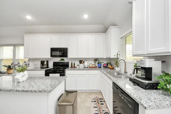 a kitchen with stainless steel appliances granite countertop a sink stove microwave and refrigerator