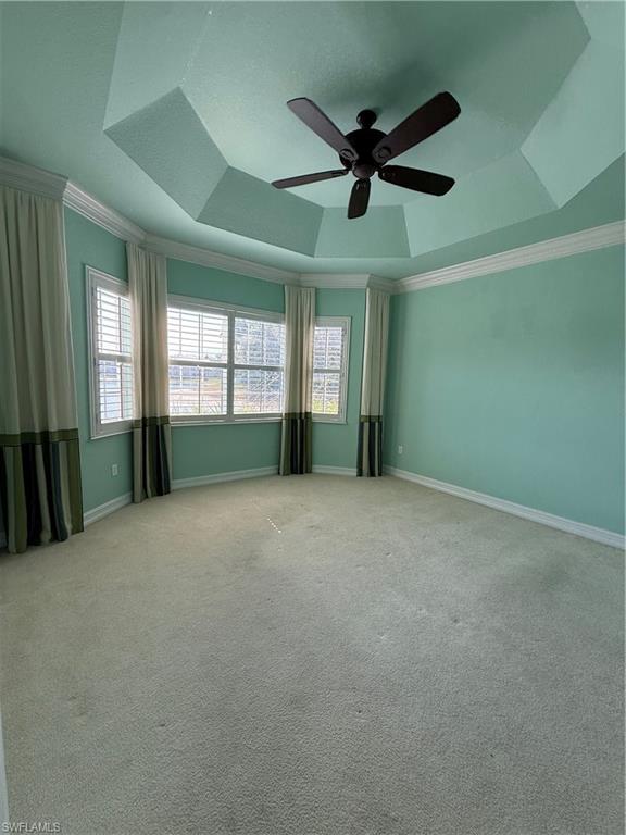 7168 Lemuria Circle, Unit 1701 Naples, FL 34109 - Photo 17 of 39 Master bedroom with a ceiling fan, carpet, healthy amount of natural light, a tray ceiling, and ornamental molding