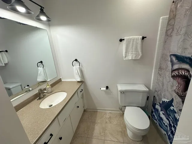 a bathroom with a granite countertop toilet sink and mirror