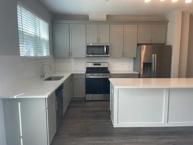 a kitchen with kitchen island granite countertop a sink cabinets and stainless steel appliances