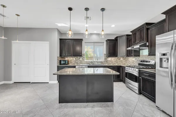 a kitchen with stainless steel appliances kitchen island granite countertop a stove a sink and a refrigerator