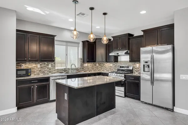 a kitchen with stainless steel appliances granite countertop a stove a refrigerator and a sink