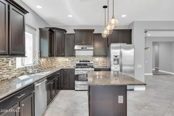 a kitchen with stainless steel appliances granite countertop a sink a stove and a refrigerator