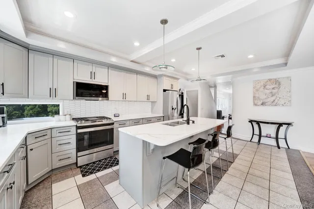 a open kitchen with stainless steel appliances granite countertop a stove top oven a sink dishwasher a dining table and chairs with wooden floor