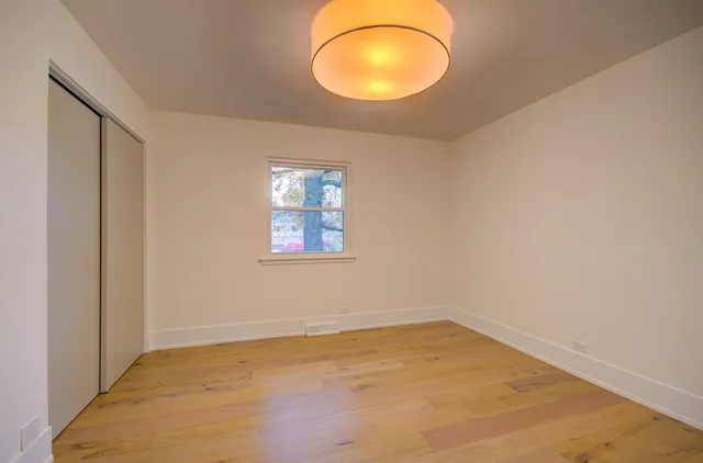 an empty room with a window and wooden floor