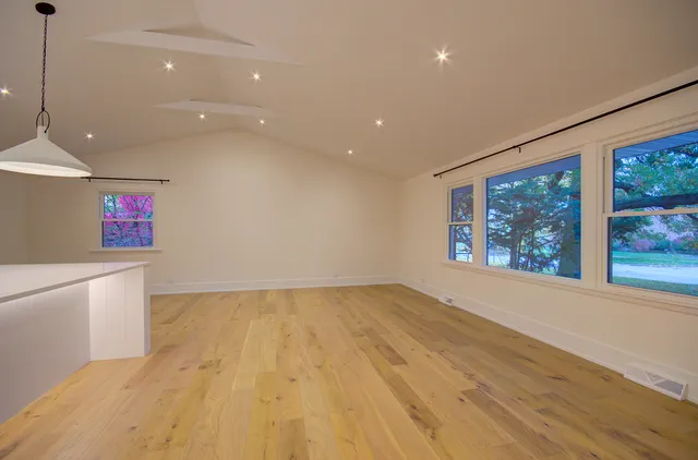 a view of an empty room with a window and wooden floor