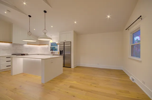 a kitchen with kitchen island a counter top space a sink stainless steel appliances and cabinets
