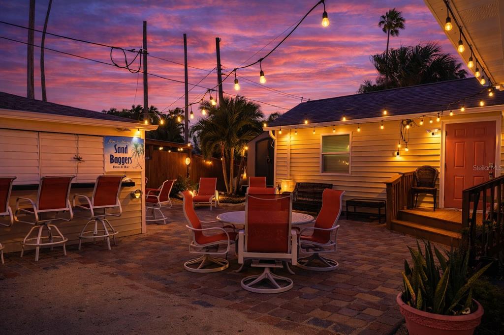 14033 Palm Street Madeira Beach, FL 33708 - Photo 32 of 41 a view of a patio with dining table and chairs with a barbeque grill and potted plants