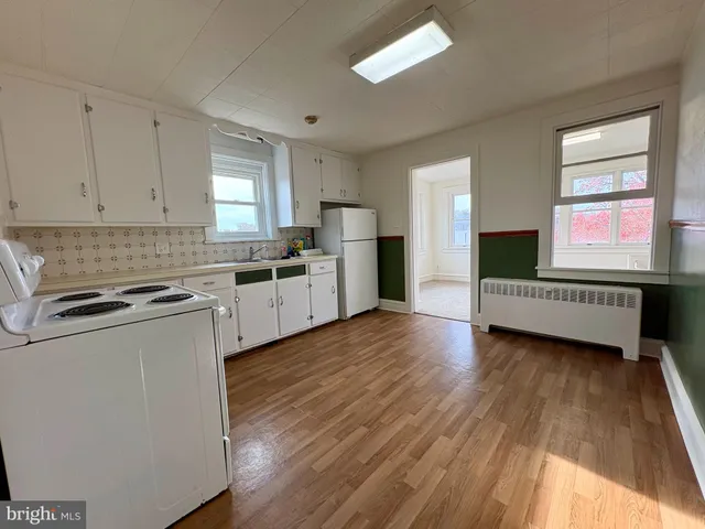 a kitchen with a wooden floor a window cabinets and stainless steel appliances