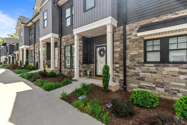 a front view of a house with garden and glass windows