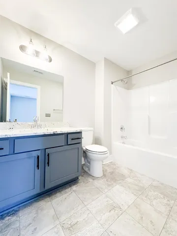 a bathroom with a granite countertop sink mirror vanity and toilet