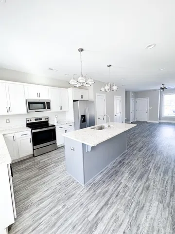 a large kitchen with granite countertop a stove top oven a sink dishwasher and a fireplace with wooden floor