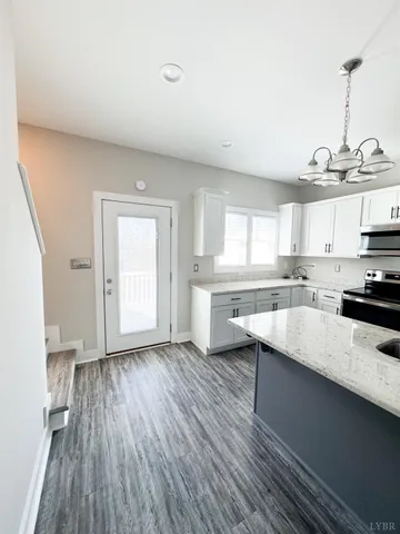 a kitchen with stainless steel appliances granite countertop a sink dishwasher a stove and white countertops with wooden floor