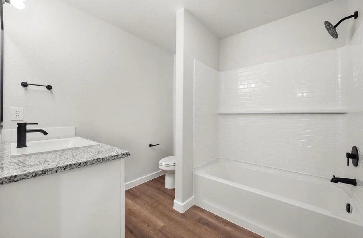 1708 145th Street Lubbock, TX 79423 - Photo 15 of 19 a bathroom with a granite countertop sink a toilet and bathtub