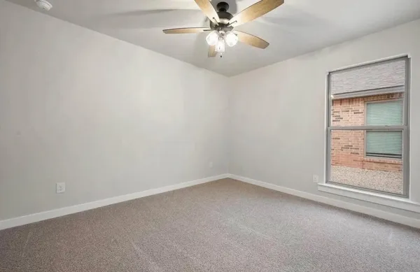 an empty room with a chandelier fan and windows