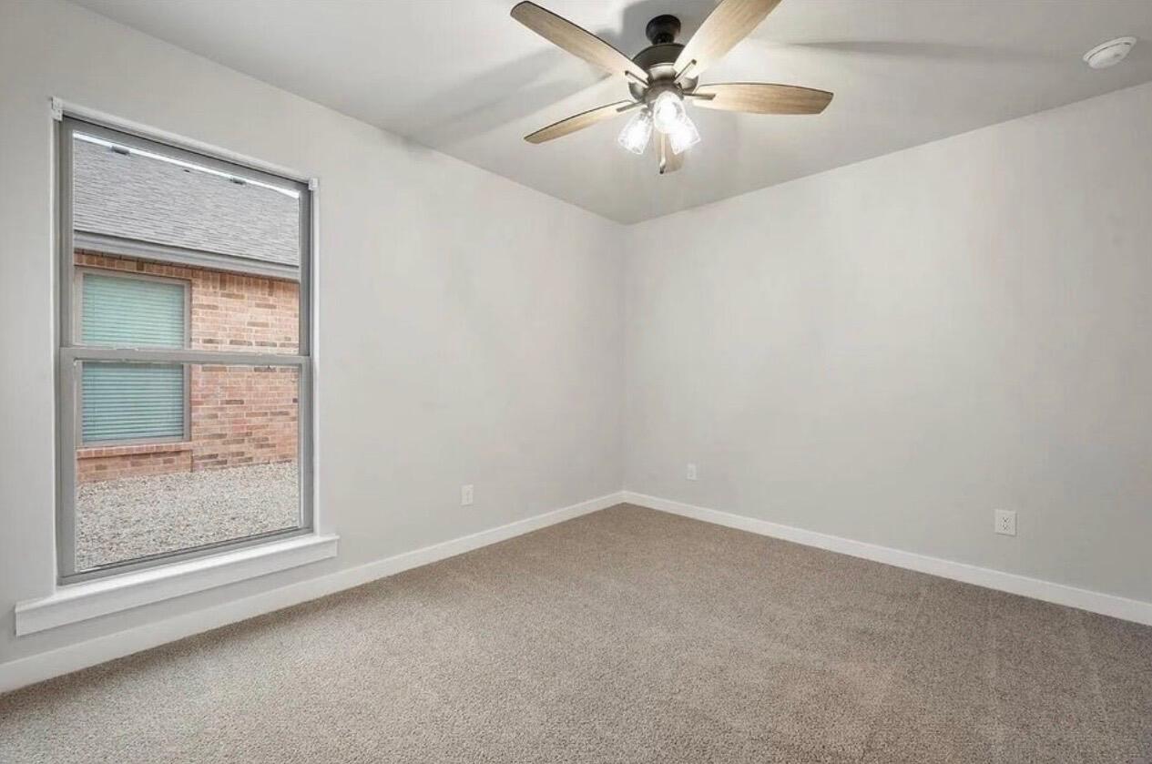 1708 145th Street Lubbock, TX 79423 - Photo 17 of 19 an empty room with a chandelier fan and windows