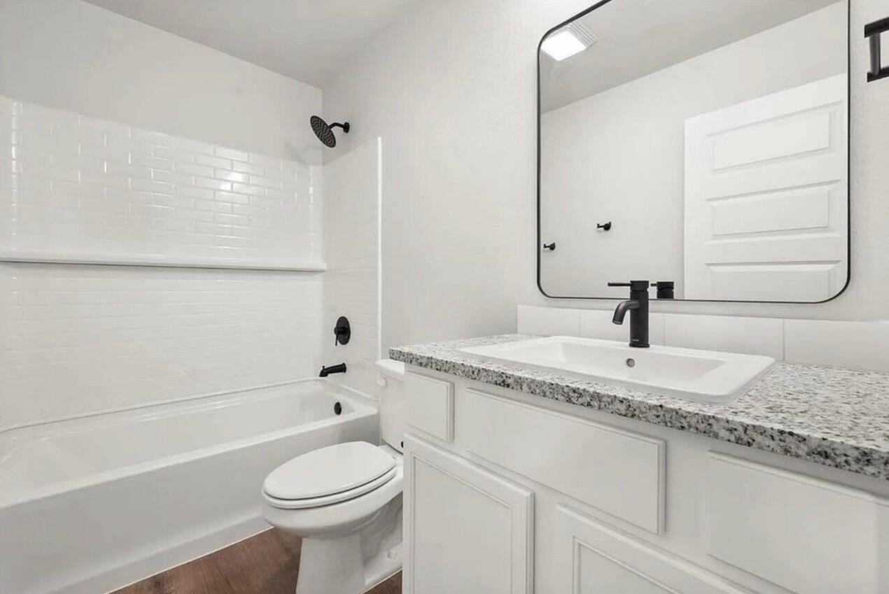 1708 145th Street Lubbock, TX 79423 - Photo 18 of 19 a bathroom with a granite countertop toilet sink and mirror