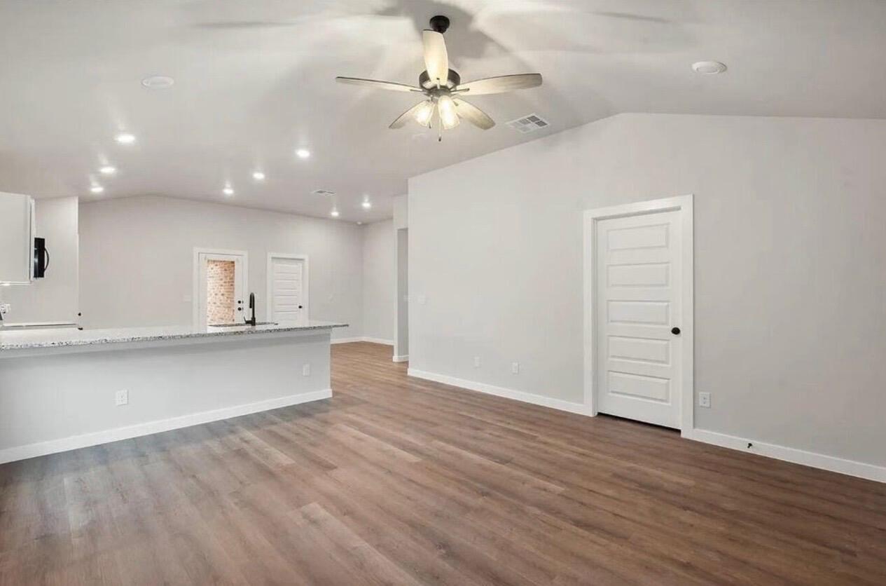 1708 145th Street Lubbock, TX 79423 - Photo 4 of 19 an empty room with wooden floor and a ceiling fan