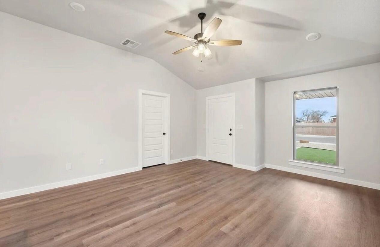1708 145th Street Lubbock, TX 79423 - Photo 6 of 19 an empty room with wooden floor chandelier fan and windows