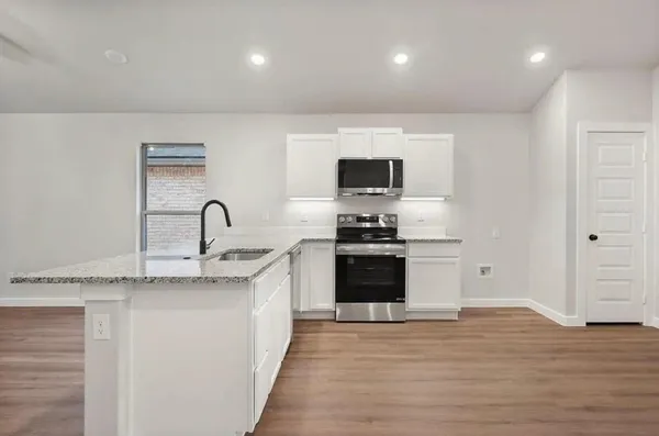 a kitchen with stainless steel appliances granite countertop a sink a stove a microwave and cabinets