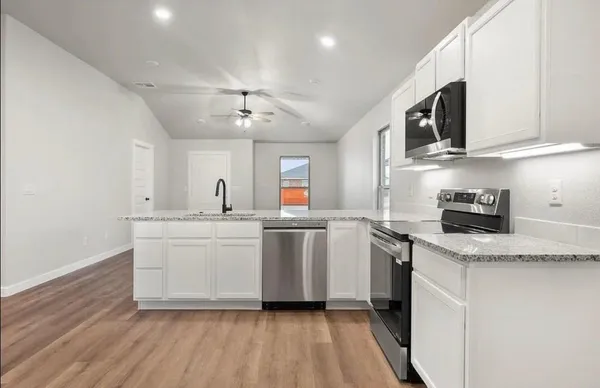 a large white kitchen with kitchen island a sink a stove a refrigerator and white cabinets