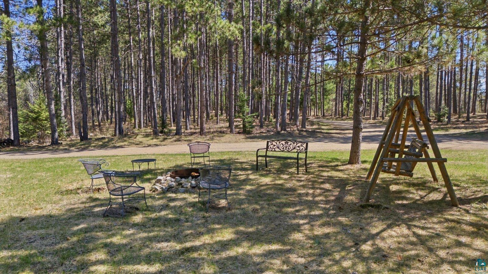7185 Giants Ridge Road Embarrass, MN 55732 - Photo 47 of 47 Expansive lawn featuring a built-in fire pit, surrounded by mature pine trees