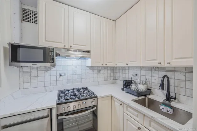 a kitchen with granite countertop white cabinets and stainless steel appliances