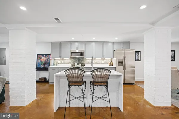 a kitchen with stainless steel appliances kitchen island granite countertop a refrigerator a stove a sink dishwasher and white cabinets with wooden floor