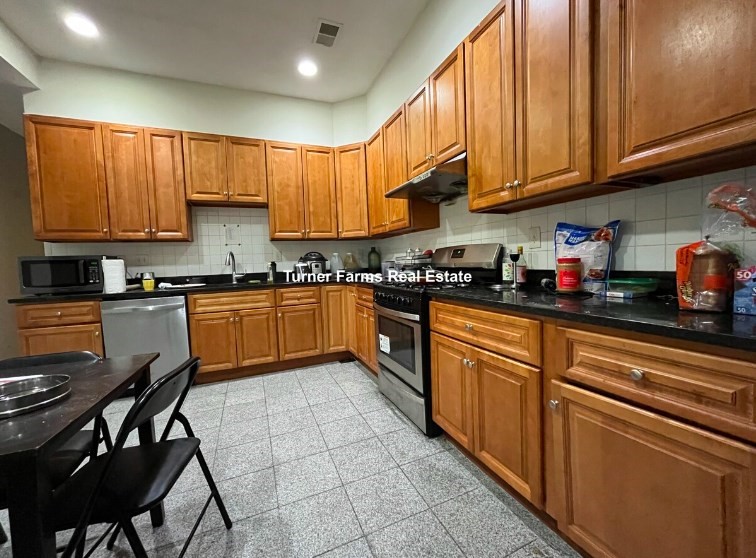 a kitchen with stainless steel appliances granite countertop a sink a stove a refrigerator cabinets and a window