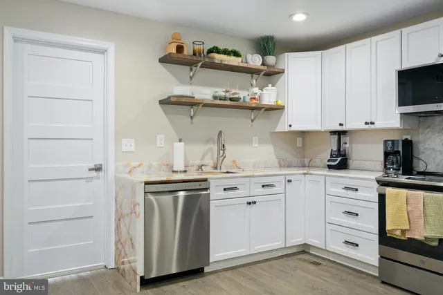 a kitchen with granite countertop a stove and white cabinets