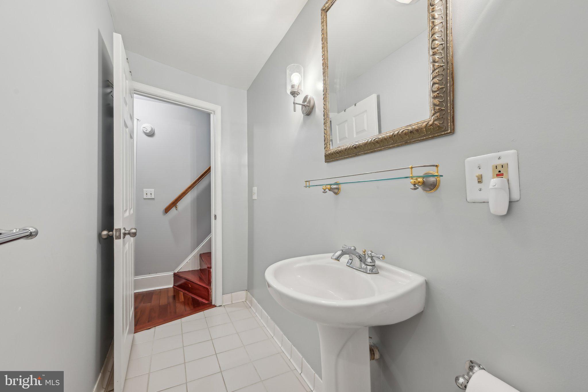 935 South Kenwood Avenue Baltimore, MD 21224 - Photo 20 of 25 a bathroom with a sink a mirror and a toilet
