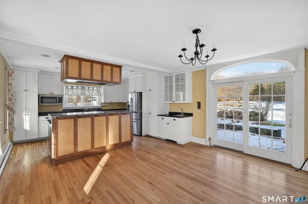 a kitchen with stainless steel appliances granite countertop a refrigerator a stove top oven a sink dishwasher and white cabinets with wooden floor