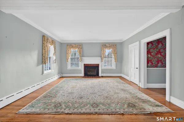 a view of an empty room with a fireplace and wooden floor