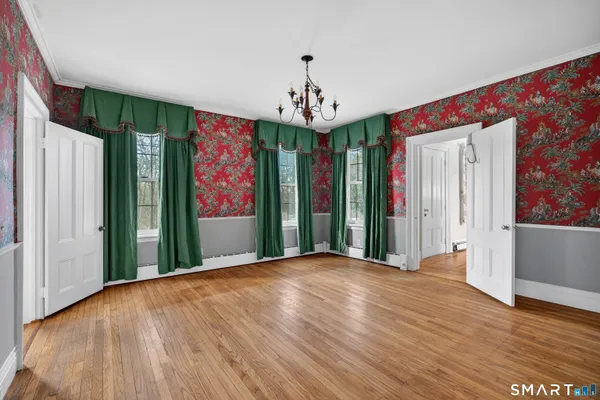 a view of an empty room with wooden floor and windows