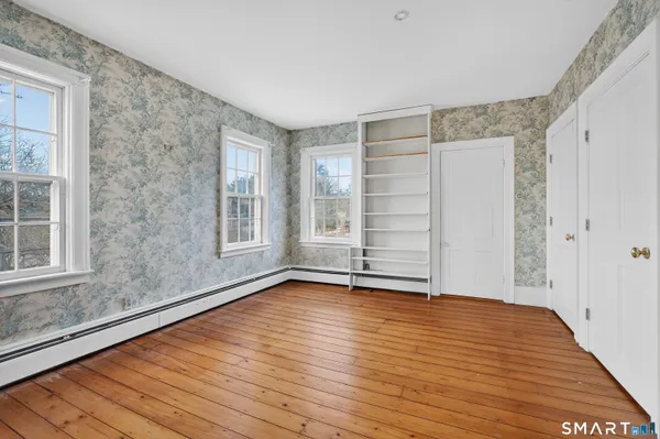 a view of an empty room with a window and wooden floor