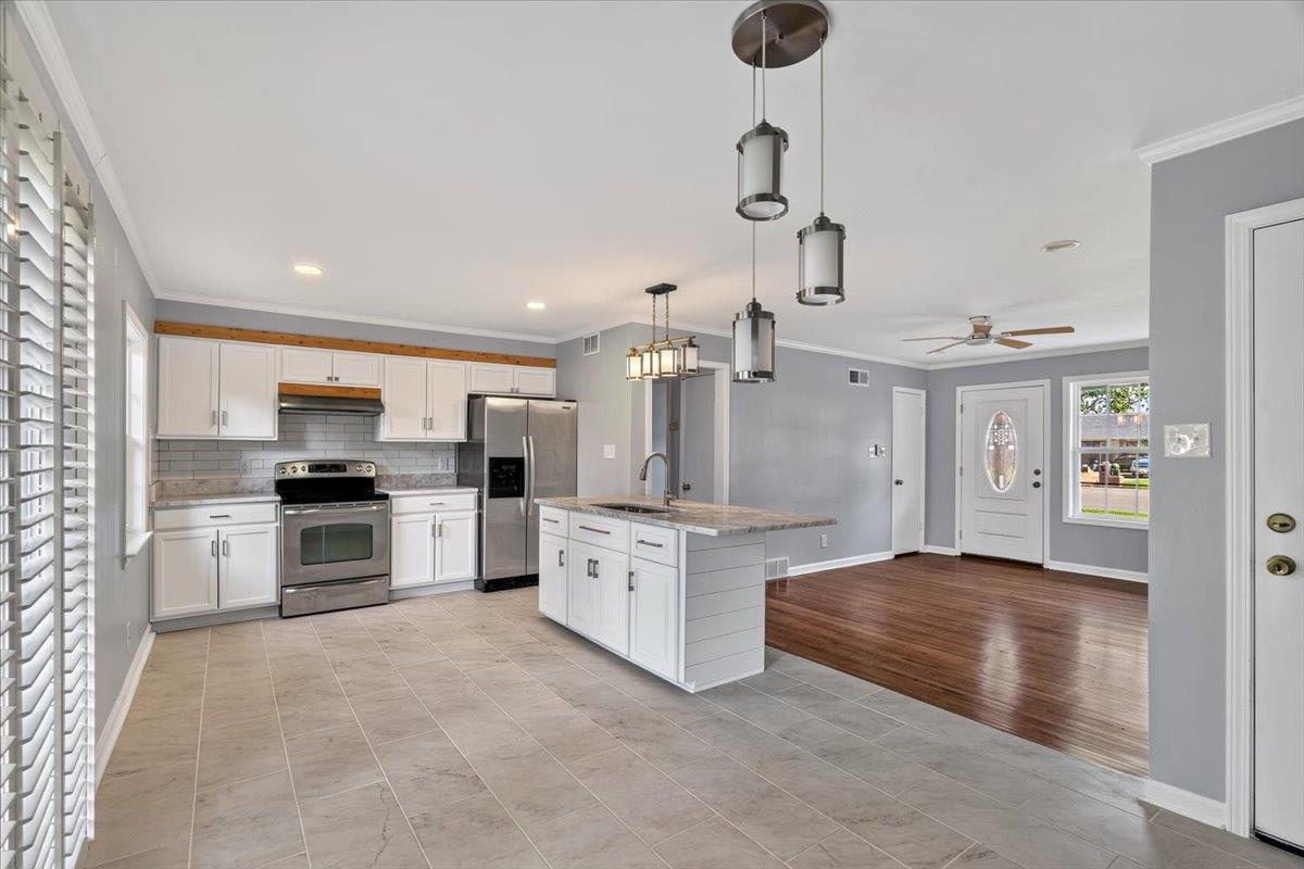 1744 West Holmes Road Memphis, TN 38109 - Photo 2 of 24 Kitchen featuring white cabinetry, stainless steel appliances, a center island with a sink, and tile flooring