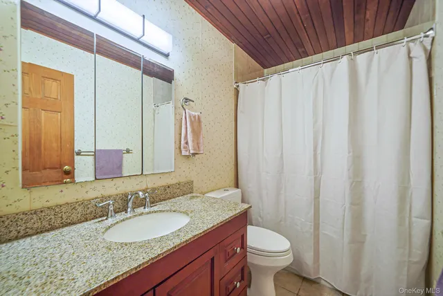 a bathroom with a granite countertop sink toilet and a mirror