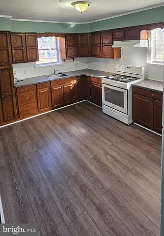 a kitchen with stainless steel appliances granite countertop a stove a sink and a wooden floors