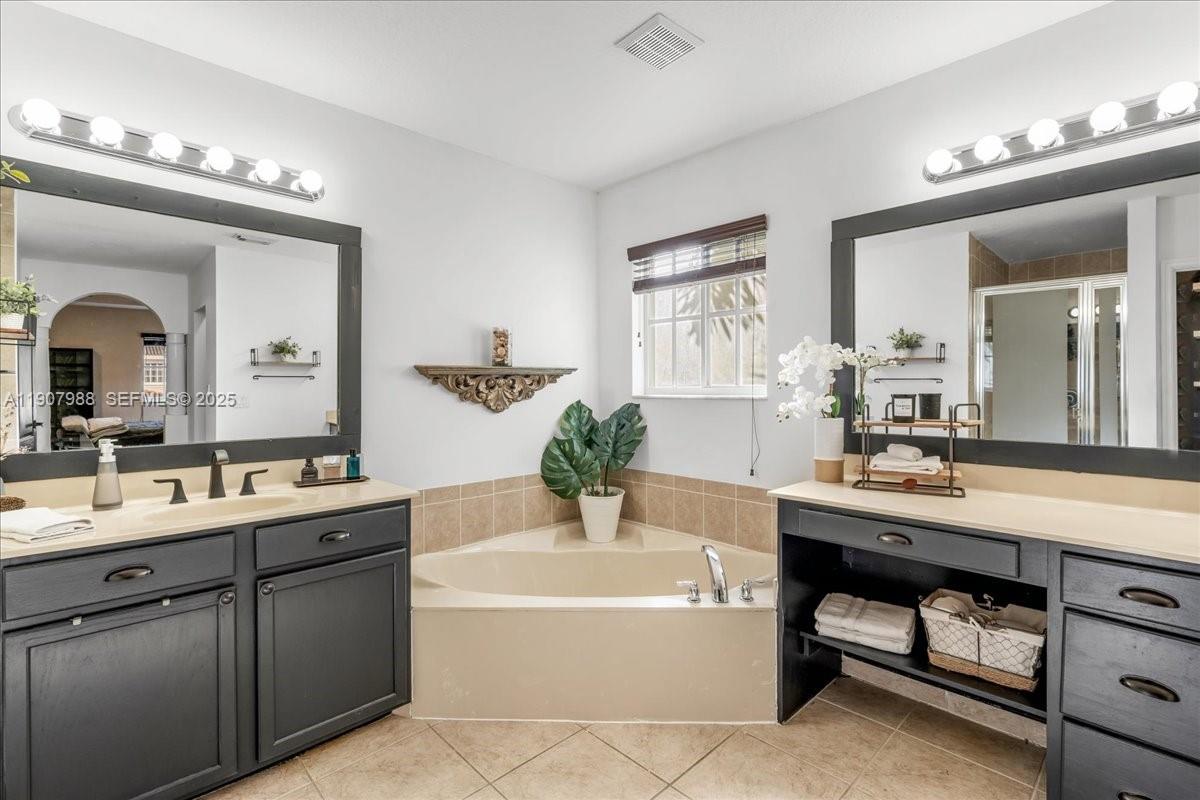 14027 Southwest 274th Terrace Homestead, FL 33032 - Photo 49 of 65 a bathroom with a tub a double vanity sink and mirror