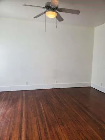 a view of an empty room with a window and wooden floor