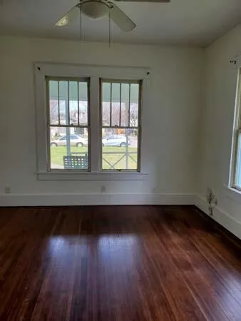 an empty room with wooden floor and windows