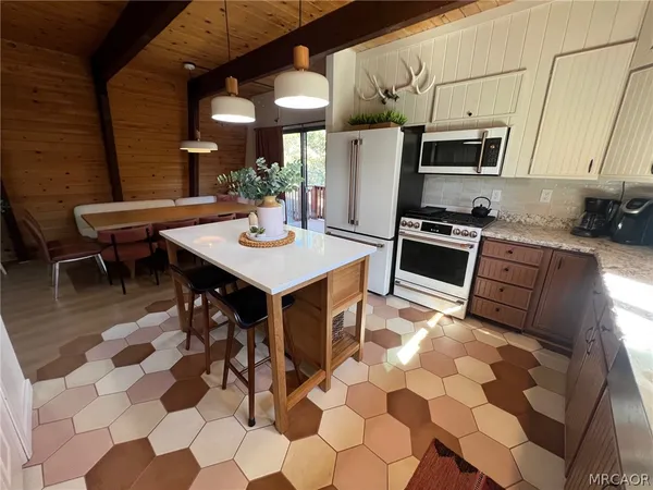 a kitchen with stainless steel appliances a sink a stove a microwave a dining table and chairs