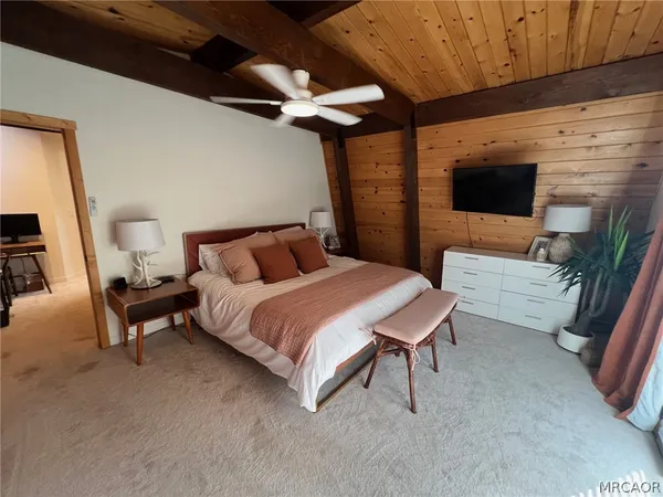 a bedroom with a bed a couch and a flat tv screen on the dresser