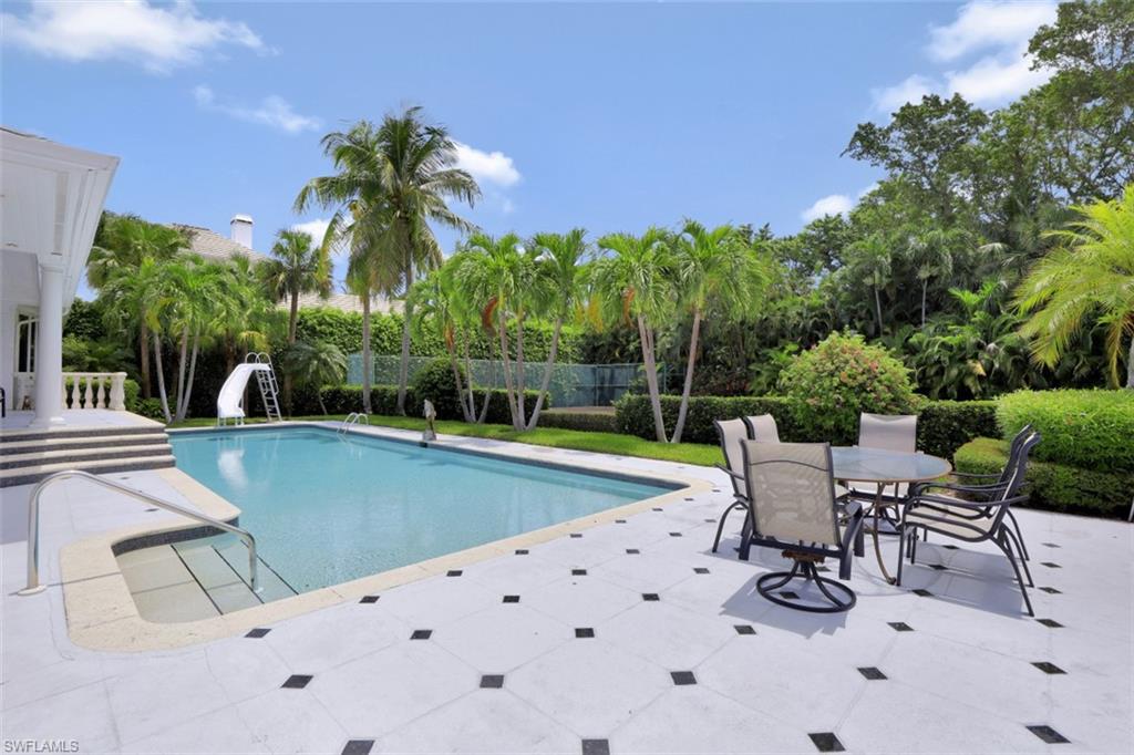 3277 Gordon Drive Naples, FL 34102 - Photo 8 of 33 a view of a swimming pool with chairs and table in the patio