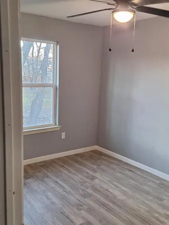 a view of an empty room with wooden floor and a window