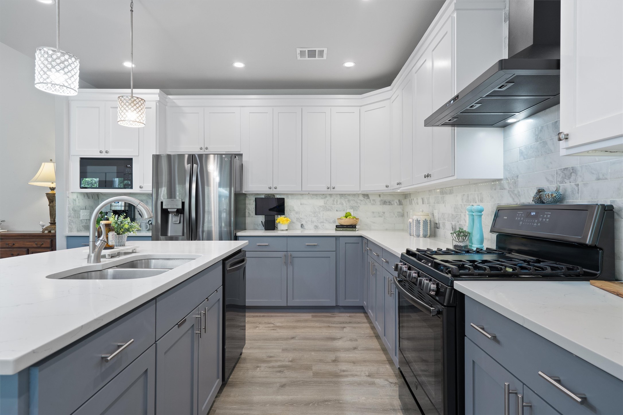 13105 Rooster Springs Road Austin, TX 78737 - Photo 5 of 38 The kitchen features two-toned cabinetry with white upper cabinets and gray lower cabinets, complemented by white countertops and a patterned backsplash