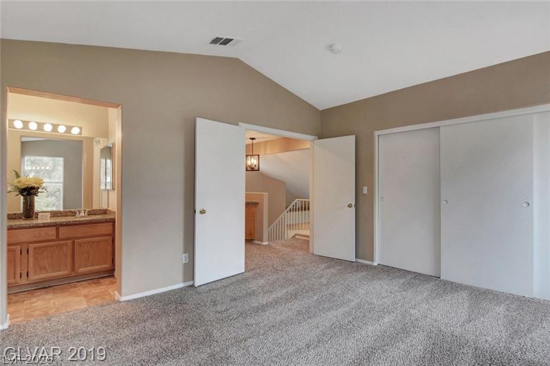 2647 Ridgewater Circle Henderson, NV 89074 - Photo 16 of 26 Vaulted ceilings elevate this comfortable bedroom with plush carpeting and an adjacent bathroom.