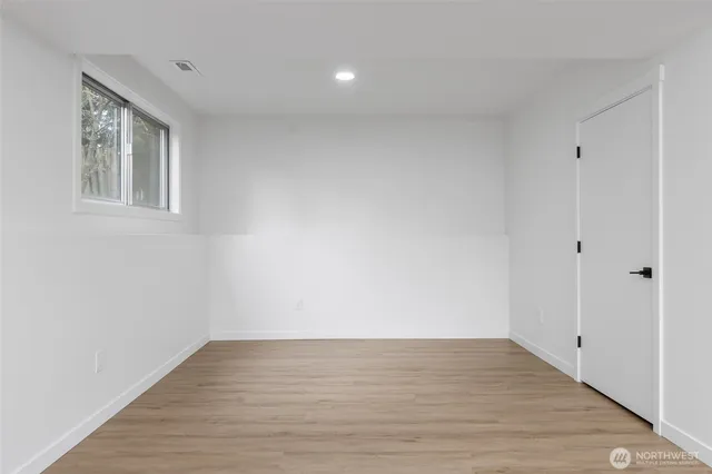 a view of an empty room with wooden floor and a window