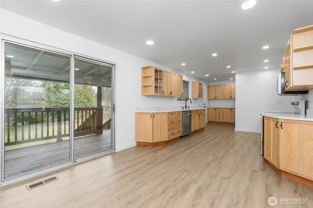 a large kitchen with stainless steel appliances kitchen island a large counter top and a wooden floors