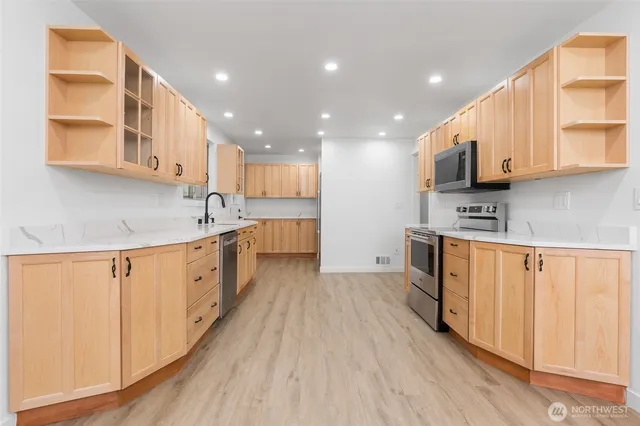 a kitchen with stainless steel appliances granite countertop a stove a sink and a refrigerator with wooden floor